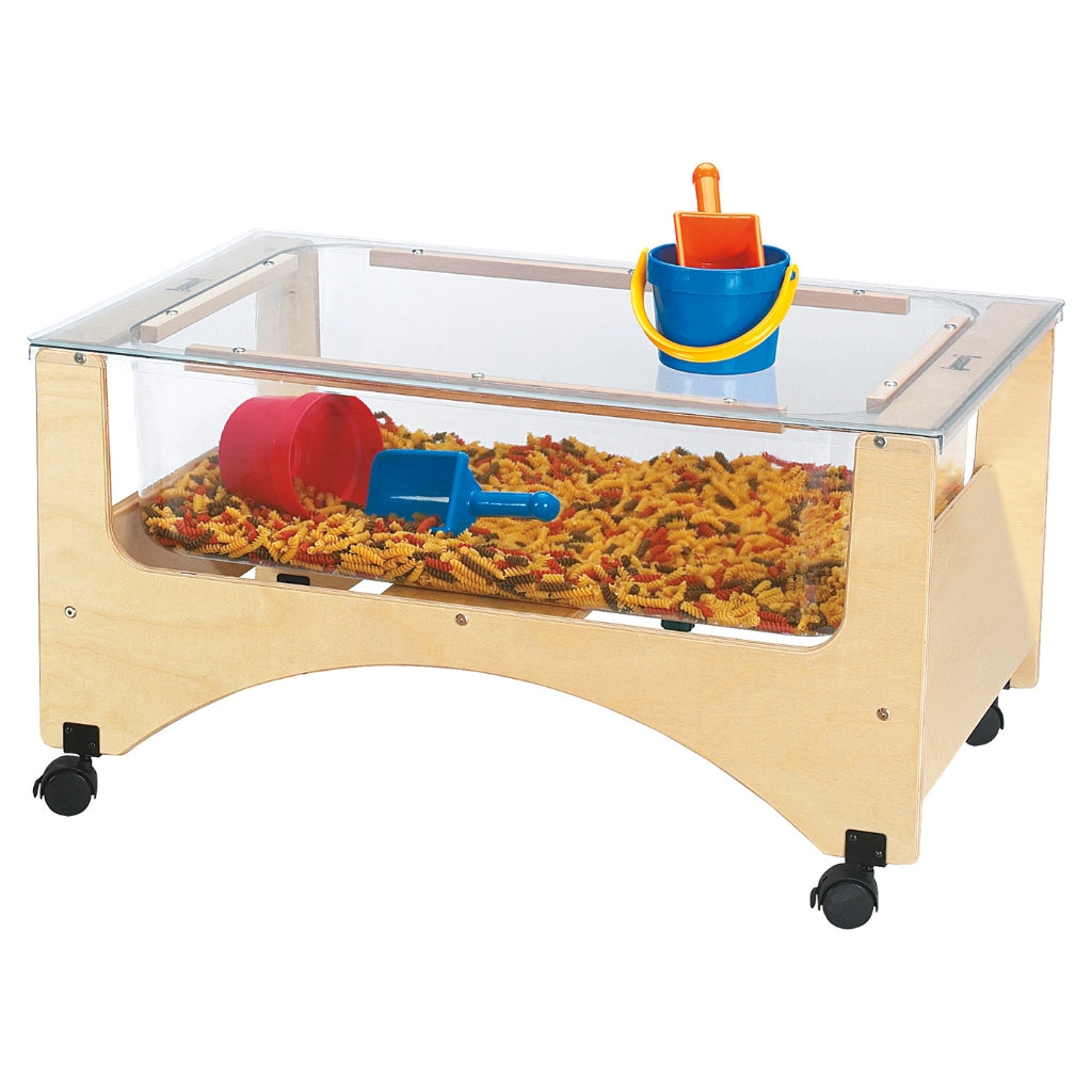 Children's sand table with transparent top, wooden base, and colourful dried pasta on a white background