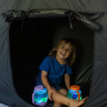 Child sitting inside a blackout sensory tent with glowing sensory play jars